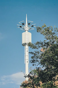 A tall telecommunications tower standing against a clear blue sky with solar panels nearby.