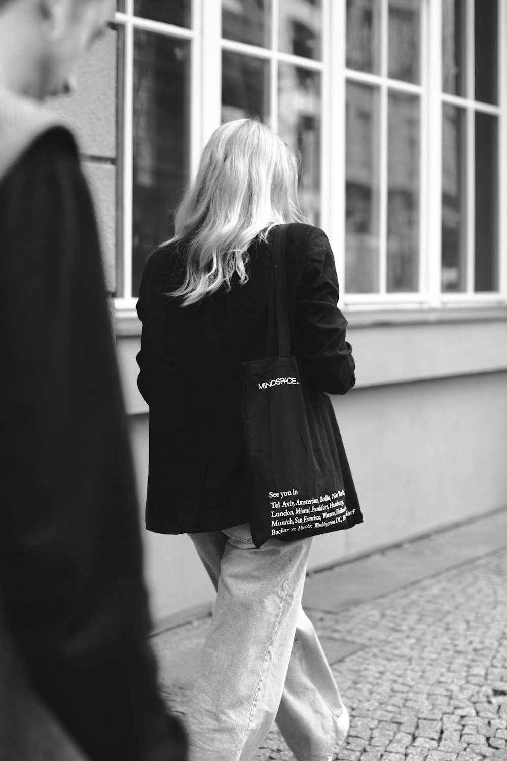 a woman walking down a street carrying a black bag