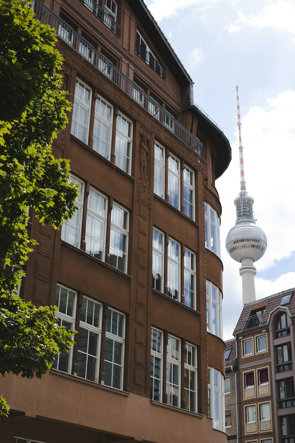 a tall brown building with a tv tower in the background
