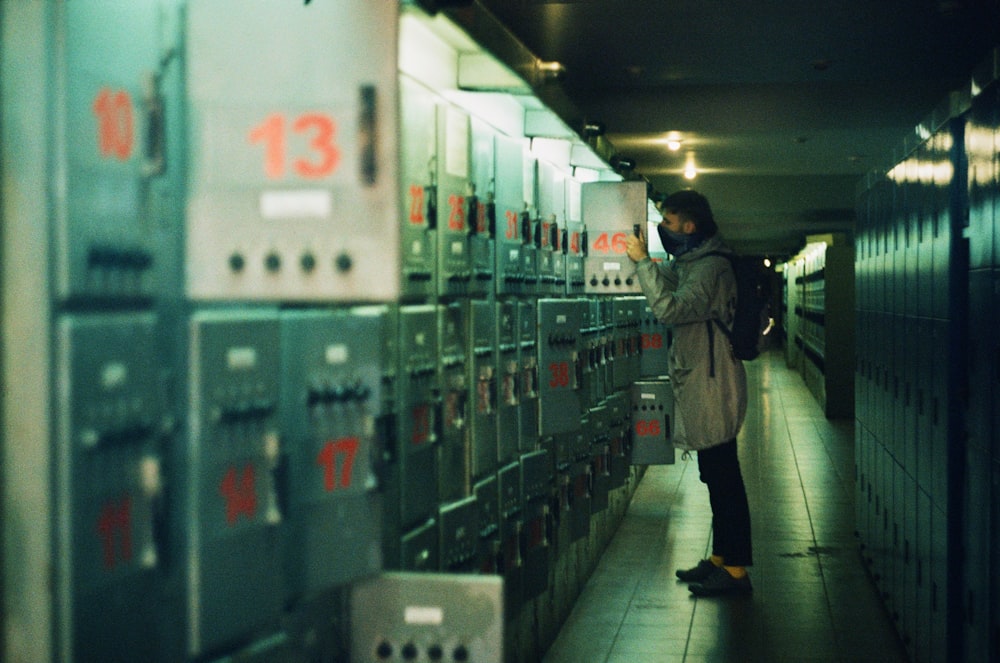 a woman standing in a hallway next to a bunch of lockers