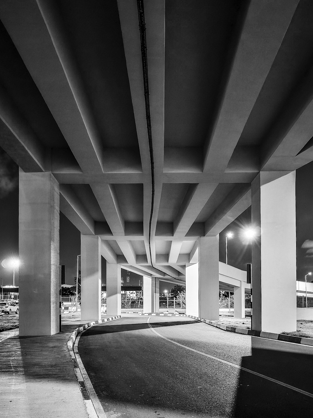 a black and white photo of a highway under a bridge