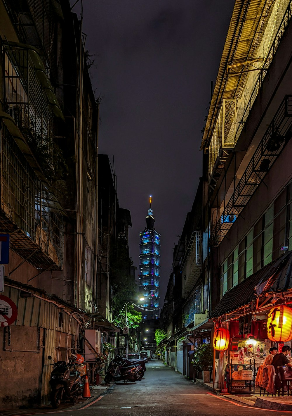 a city street at night with a tall building in the background