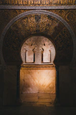 Elegant golden Islamic geometric archway softly illuminated against a deep emerald background.