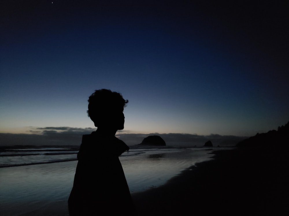 una persona in piedi su una spiaggia di notte