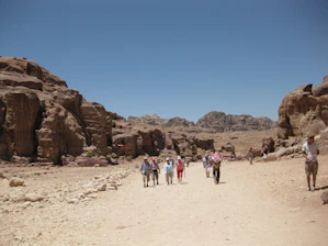 A group of travelers exploring colorful rock formations under a clear blue sky.