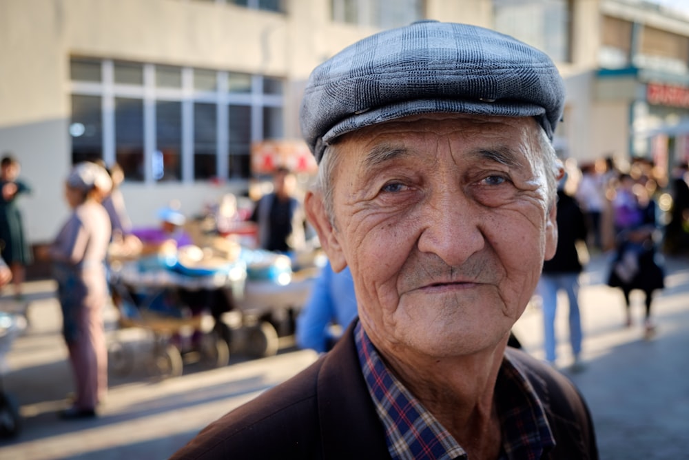 an old man with a hat on standing in front of a crowd of people