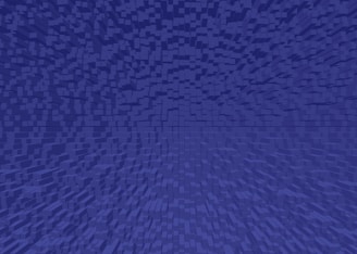 A digital artwork featuring a pattern of small, uniformly-shaped cubes arranged in a gradient, creating a sense of depth and perspective. The cubes are uniformly colored in shades of blue.