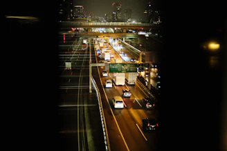 Nighttime shot of a highway with trucks moving steadily, illuminated by streetlights.