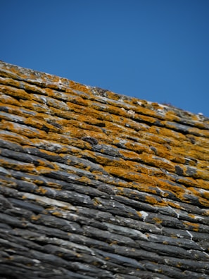 Before and after photo of a slate roof renovation on a traditional house.