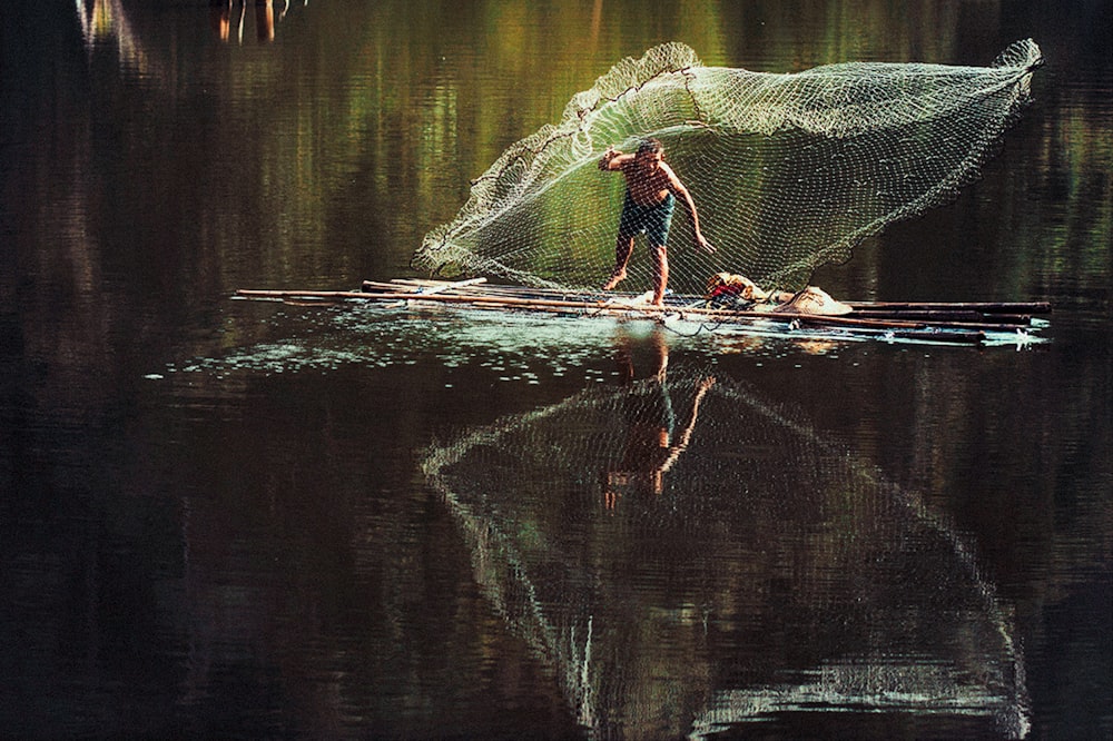 a man standing on a boat with a net over his head