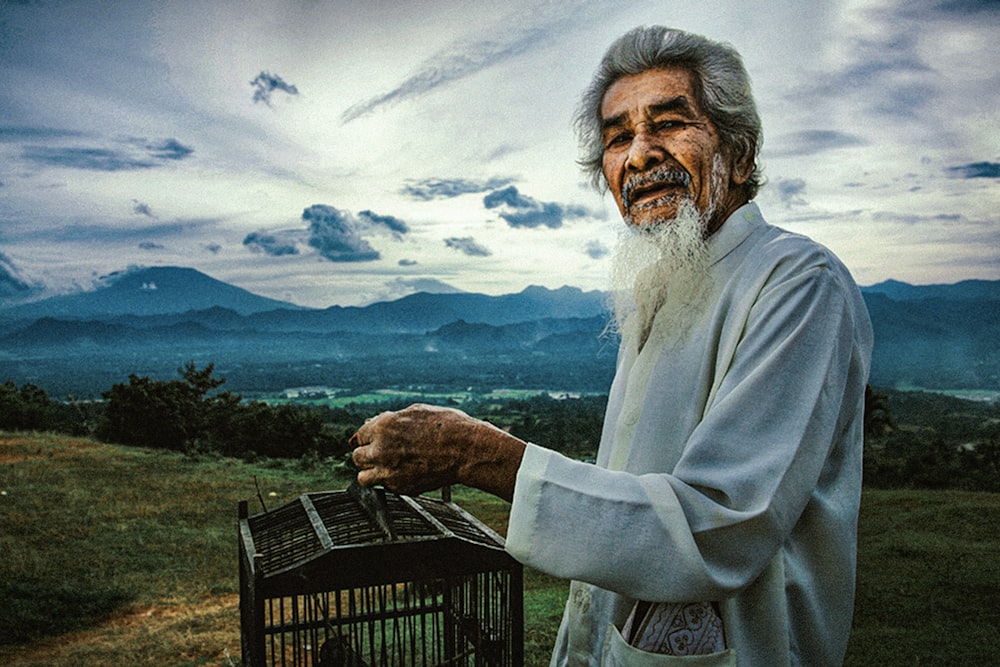 a man with a long white beard holding a birdcage