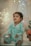 A young child wearing light blue pajamas sits in a cozy setting adorned with soft, ambient fairy lights. The child holds a small toy and appears to be looking slightly upward with a curious and engaging expression. The background includes a sheer curtain and a plush toy shaped like a sea creature, adding to the whimsical atmosphere.