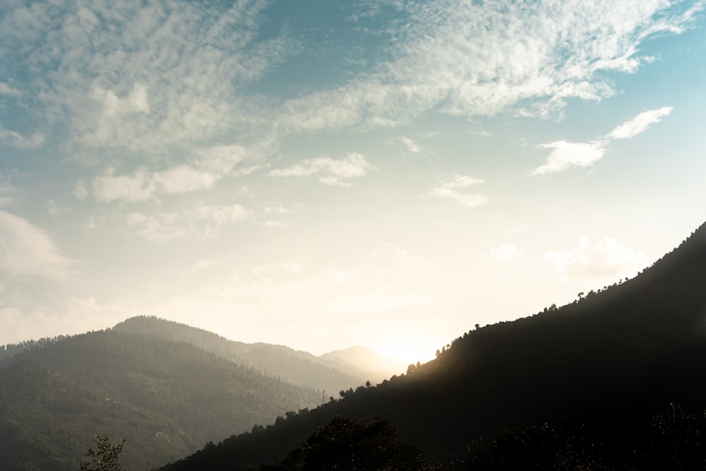 the sun shines through the clouds over the mountains