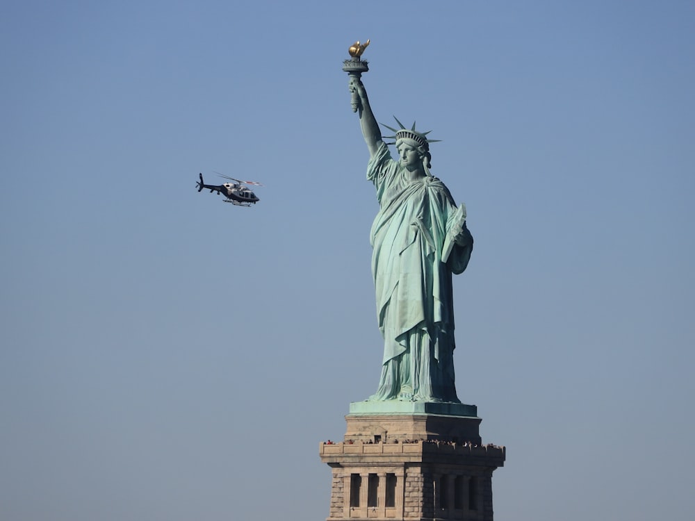 a helicopter flying over the statue of liberty