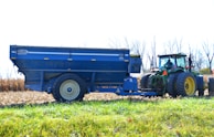 A freshly cleaned agricultural trailer parked near a green field under blue skies.