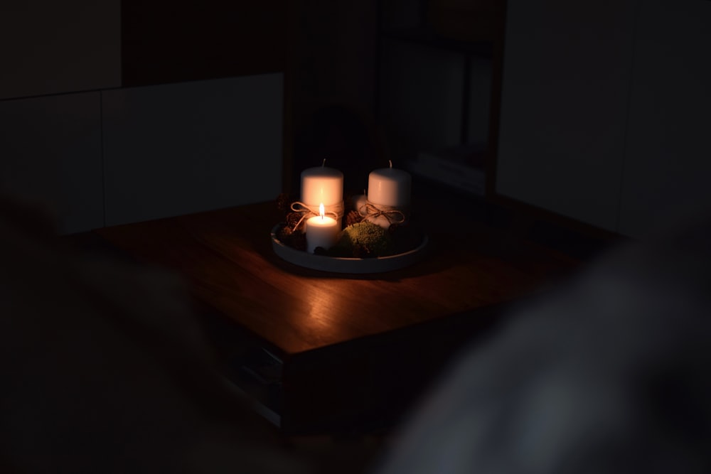 two candles sitting on a plate on a table