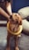 A golden retriever wearing a yellow ring around its neck looks up while a person gently holds its head.