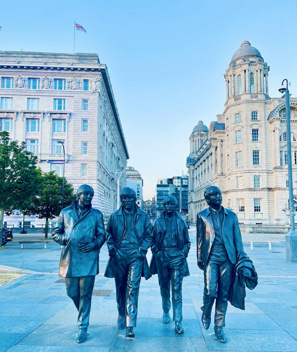 un groupe de statues de trois hommes marchant sur un trottoir