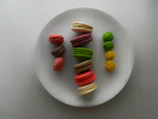 Colorful assortment of macarons arranged neatly on a white platter.