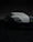 Close-up of a sleek black sports car with a glossy finish under white LED lights in a dark studio.