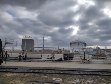 A panoramic view of a sprawling chemical plant with tanks and pipelines under a moody, industrial sky.