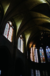 Intergenerational worship with hands raised, bathed in soft emerald light from stained glass.