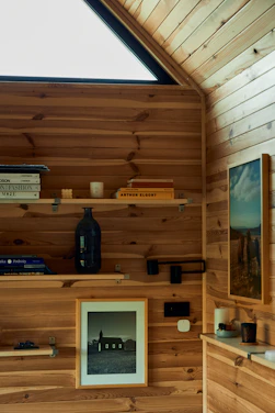 A cozy living room corner featuring a walnut floating wall shelf with books and decor.