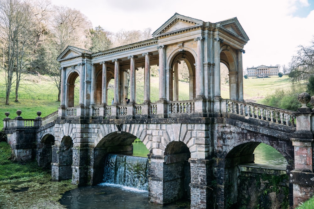 a stone bridge over a small stream in a park