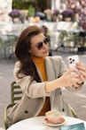a woman sitting at a table taking a picture with her phone