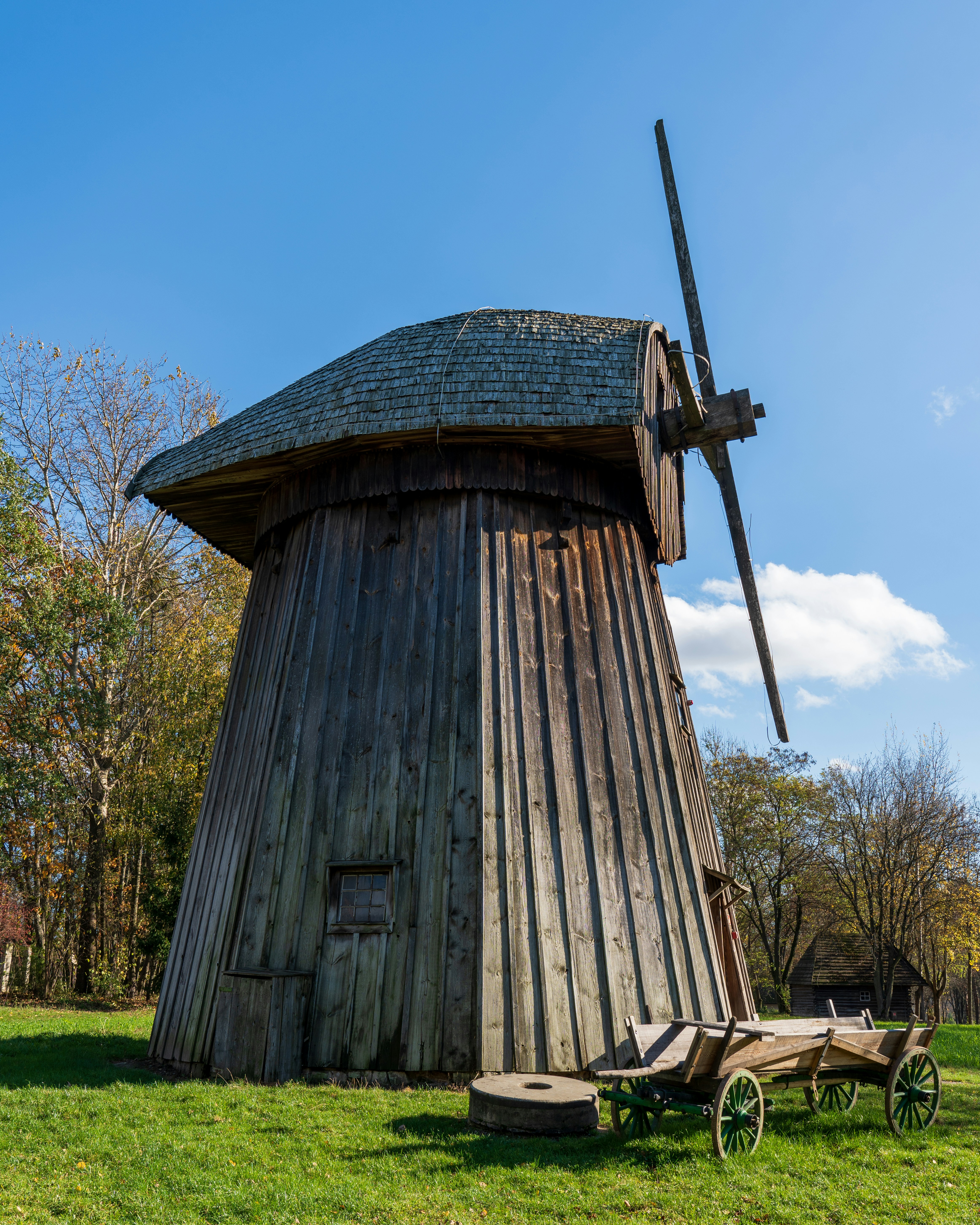 an old wooden windmill with a wooden cart in front of it