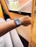 A person's wrist wearing a smartwatch is visible in a cozy room setting. The soft light coming through the window illuminates the area, highlighting the fabric strap of the watch. The room appears comfortable with curtains that gently filter the natural light.