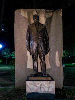 Bust of a modern Albanian historical figure with a blurred city backdrop.