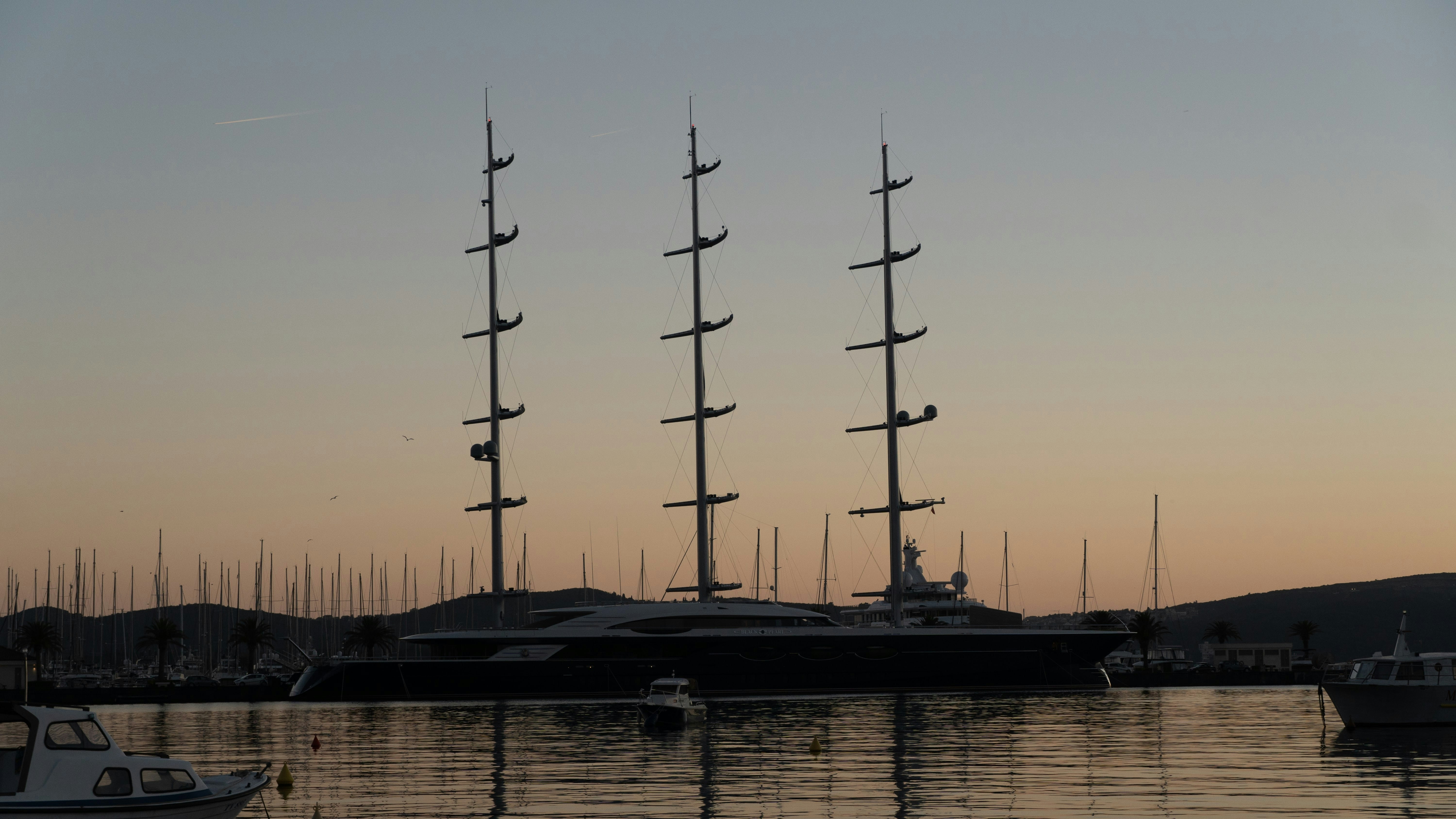 Superyacht on dark moody sea at dusk, deep blue water, atmospheric low light, architectural silhouette