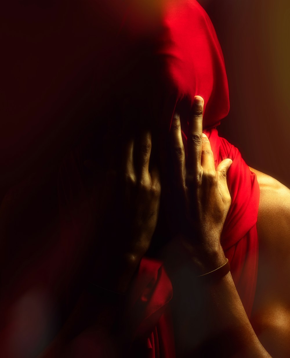 a person in a red hoodie covering their face