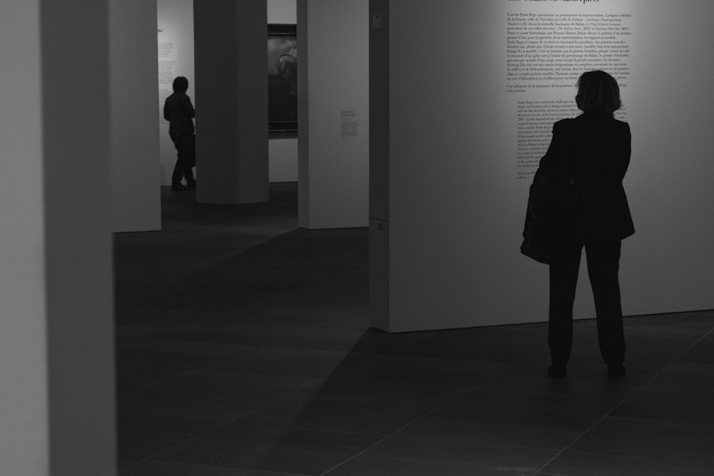 a woman standing in front of a wall in a museum