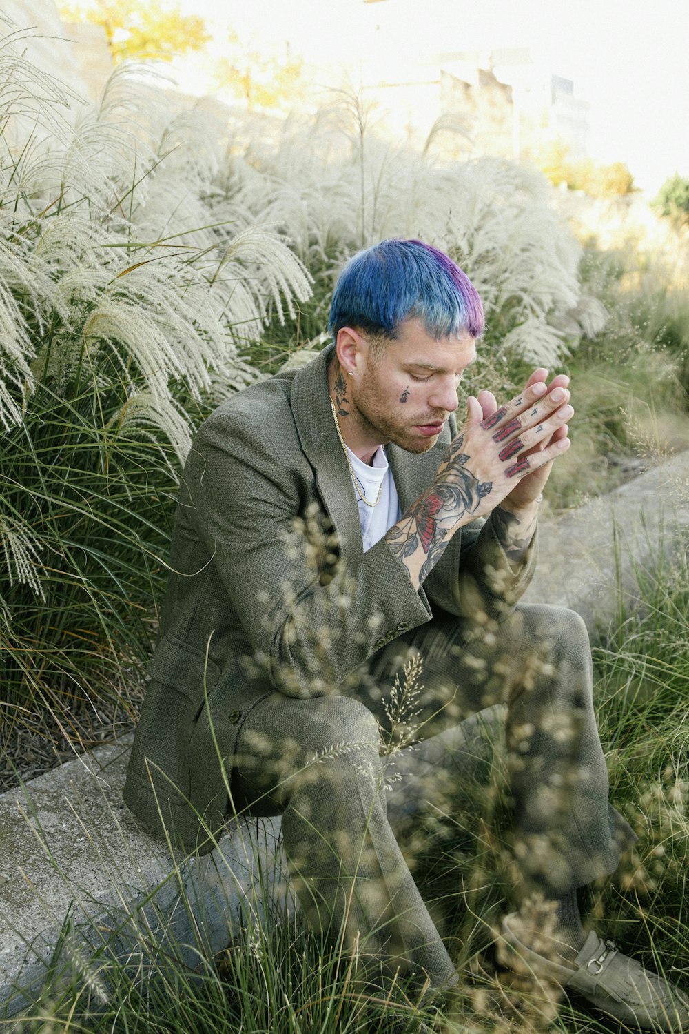 a man with blue hair sitting on a rock