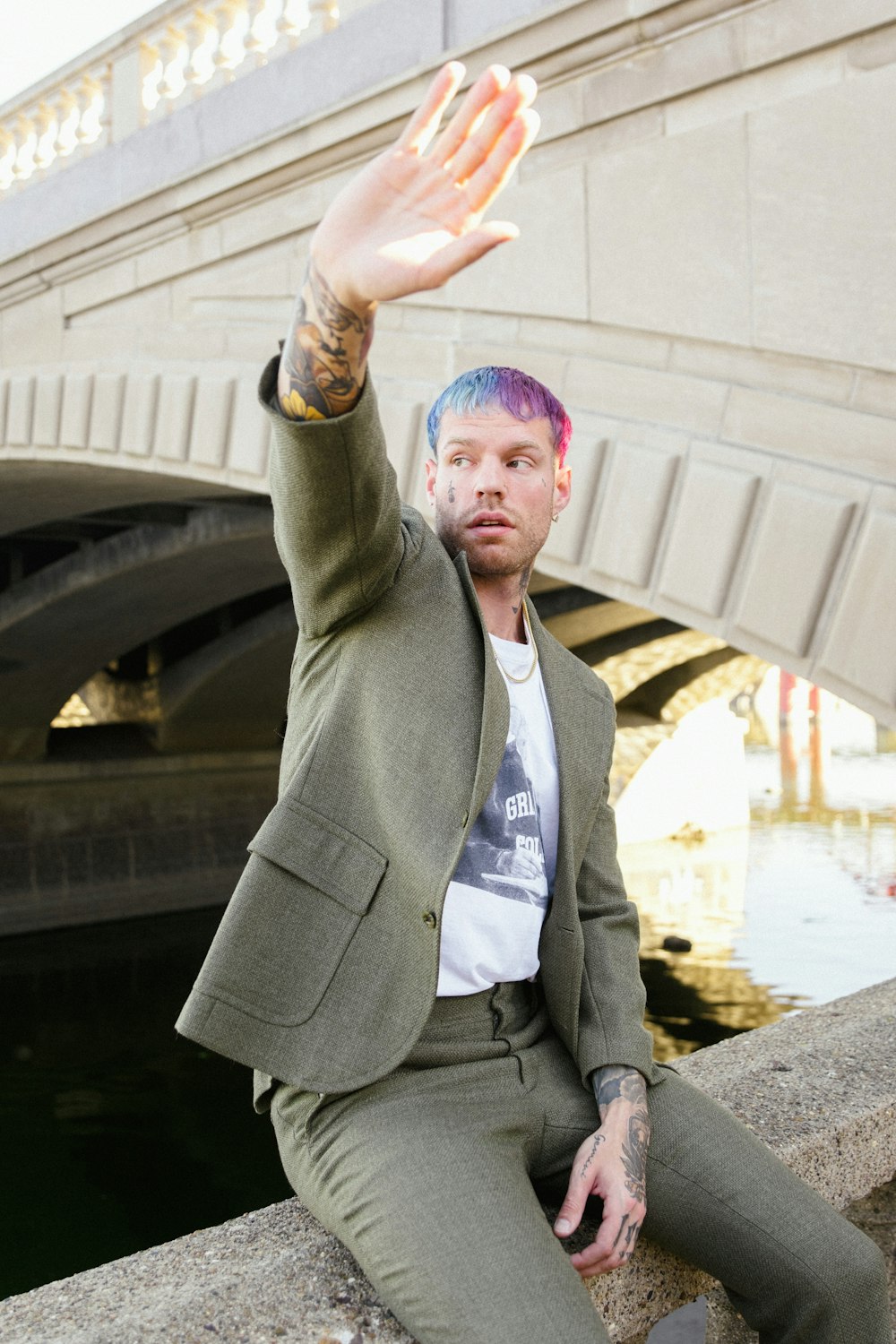 a man sitting on a ledge with his hand in the air