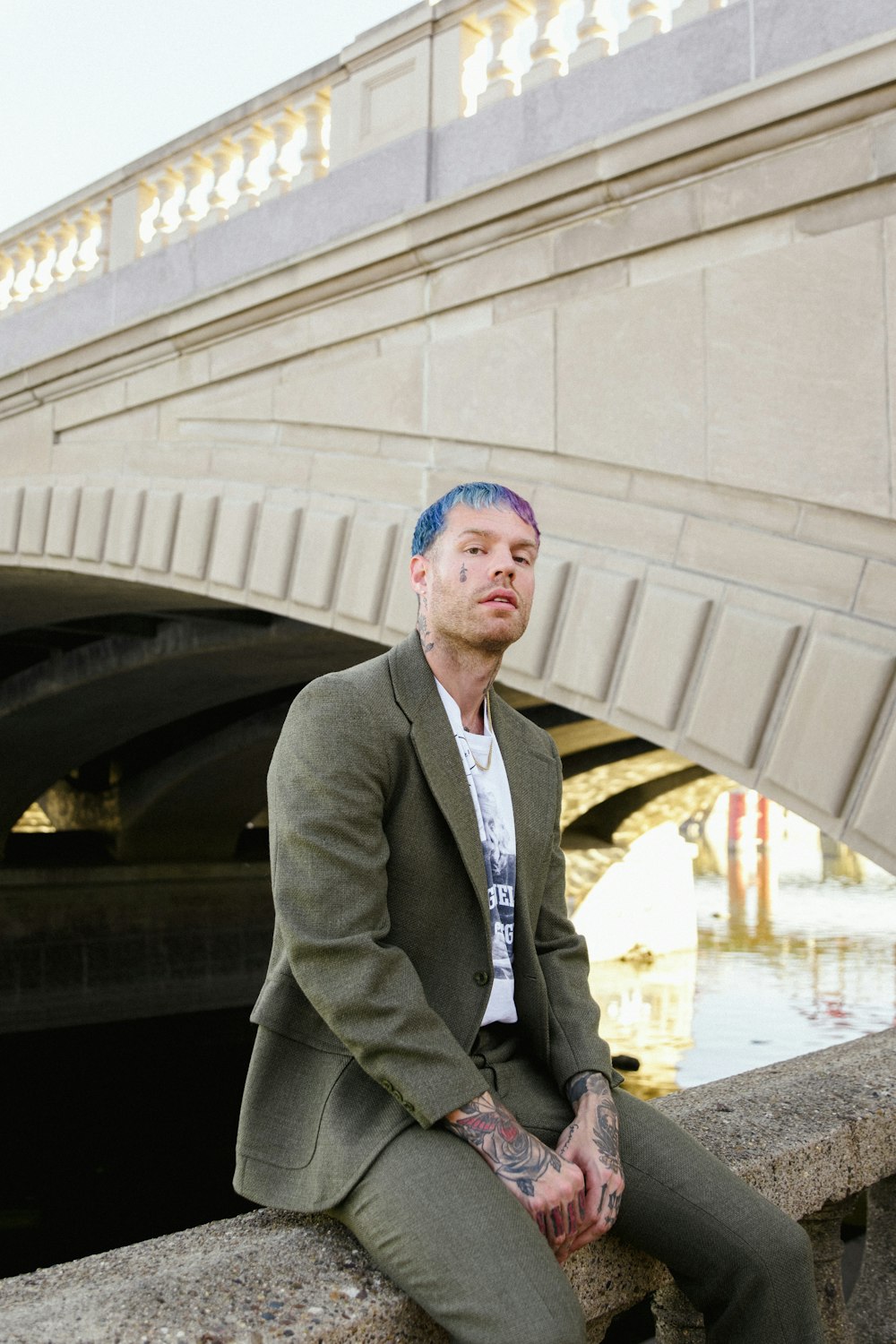 a man sitting on a ledge with a bridge in the background