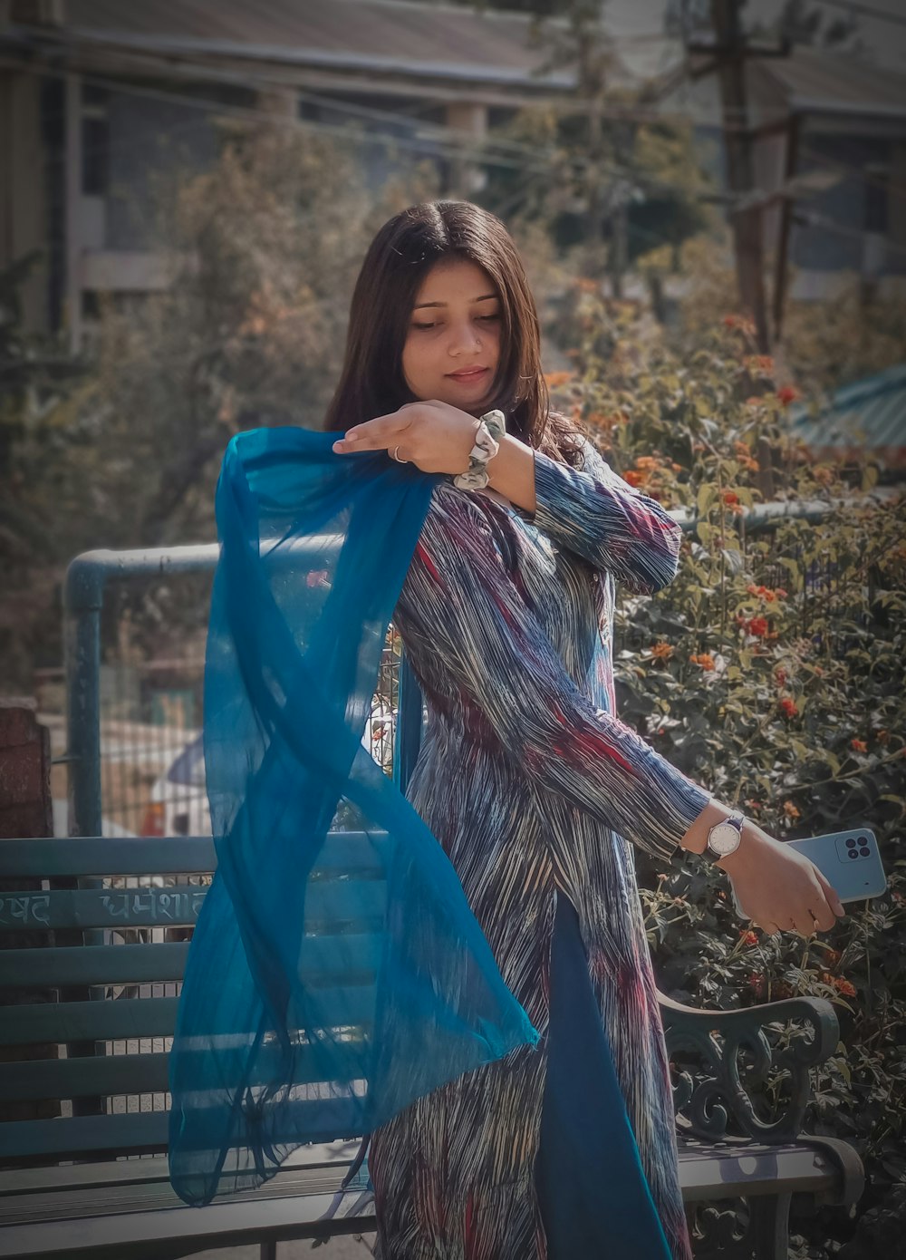 a woman standing on a bench holding a blue scarf