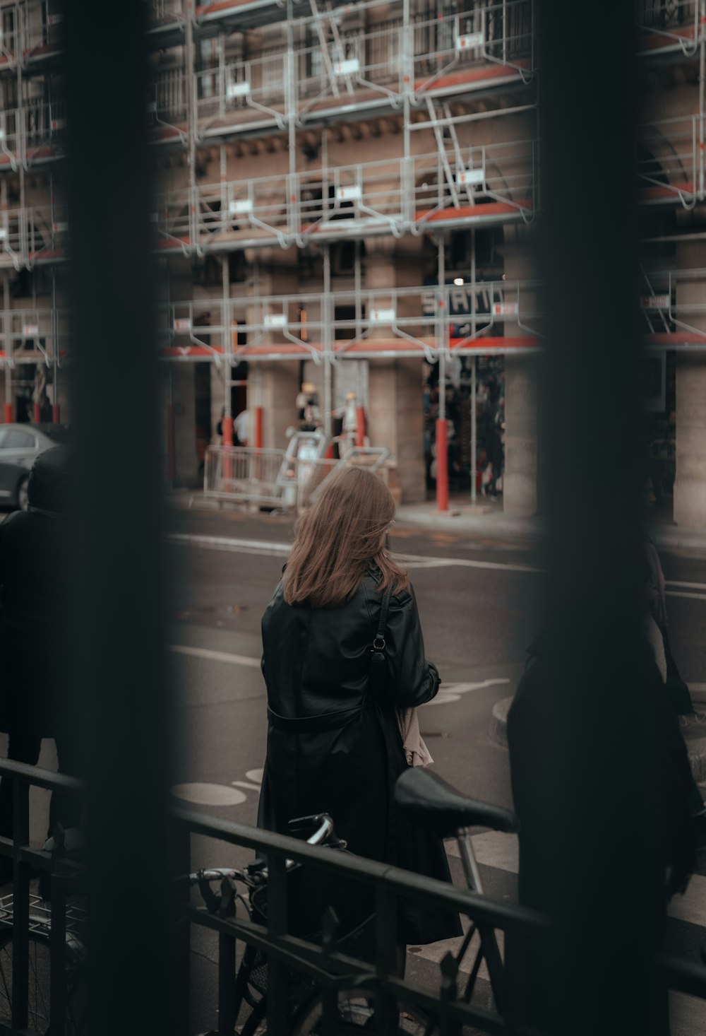 a woman riding a bike down a street next to a tall building