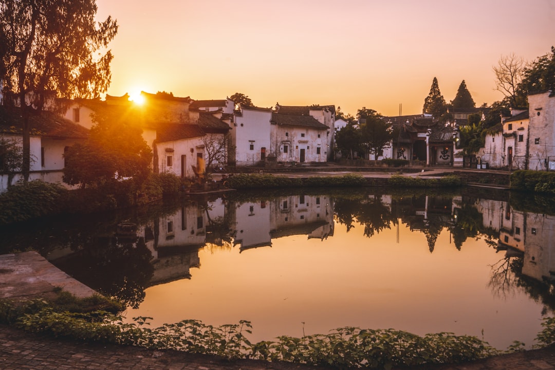 the sun is setting over a small pond,