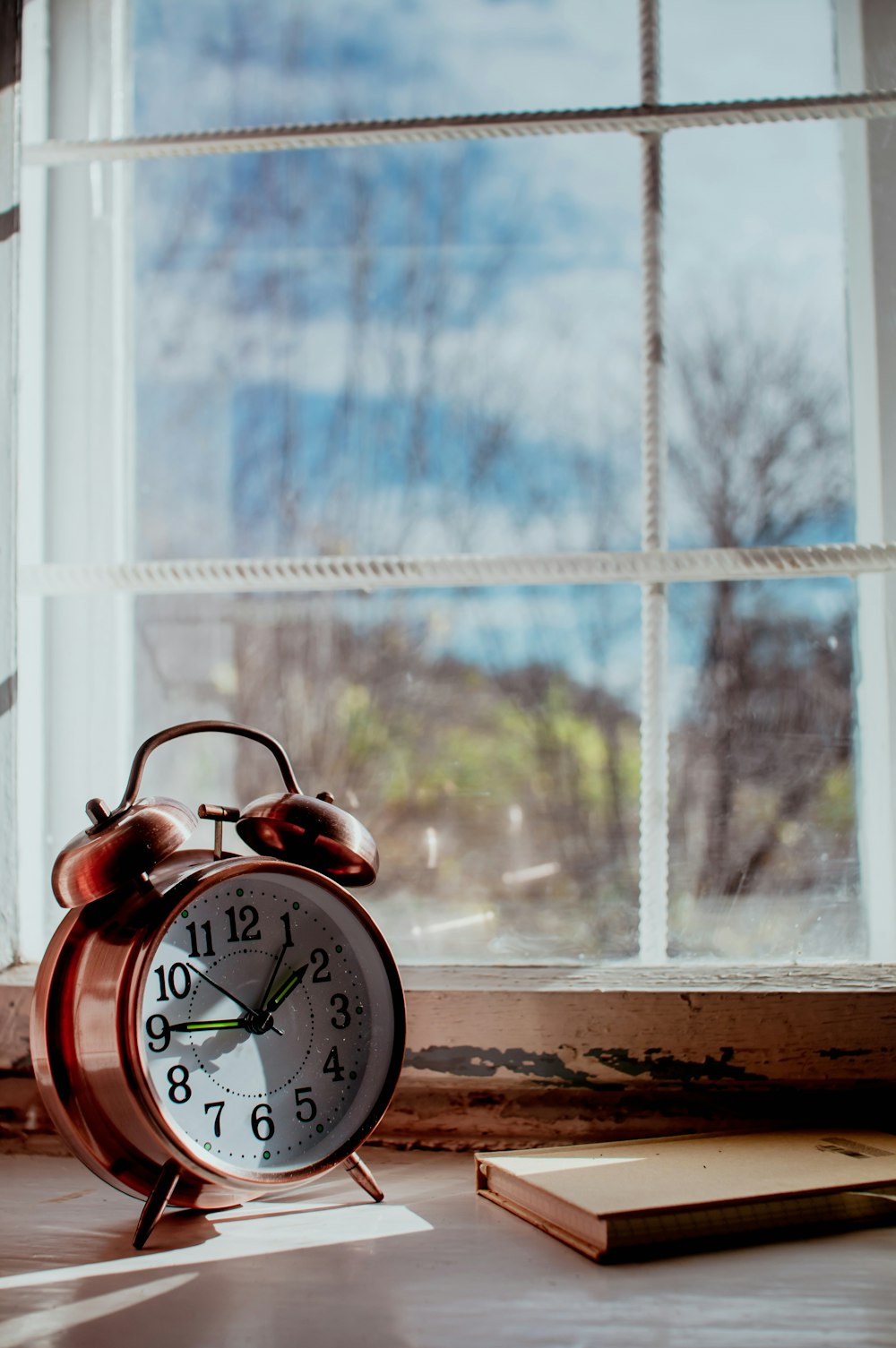 a red alarm clock sitting next to a window