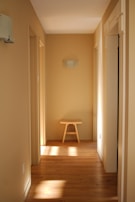 Sunlit hallway with newly painted soft beige walls and polished hardwood floors, inviting and warm.