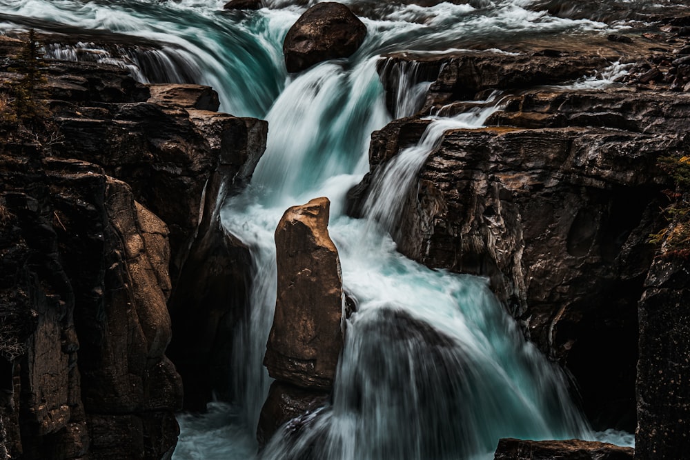 a waterfall is flowing over rocks into a body of water
