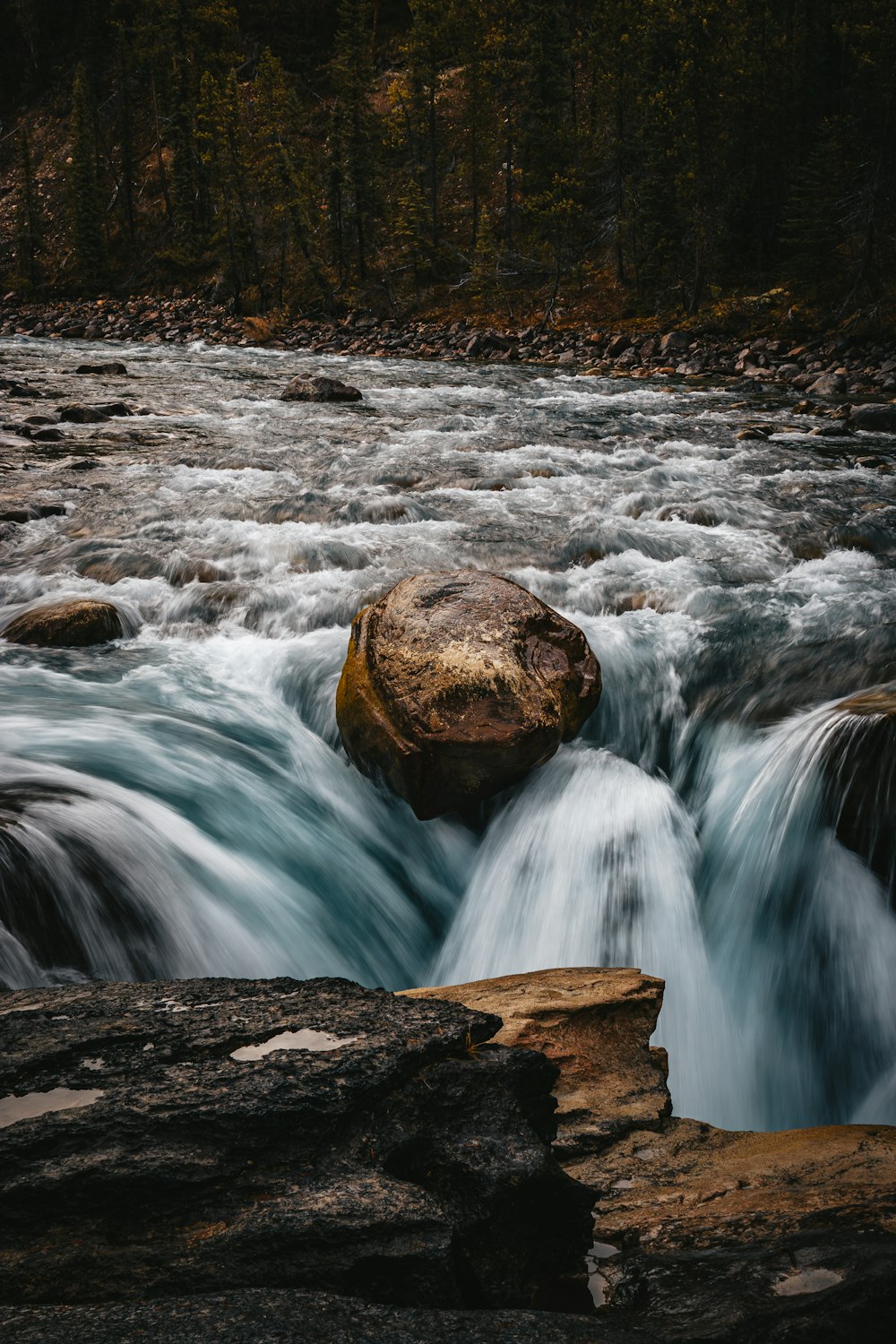 a large rock sitting in the middle of a river