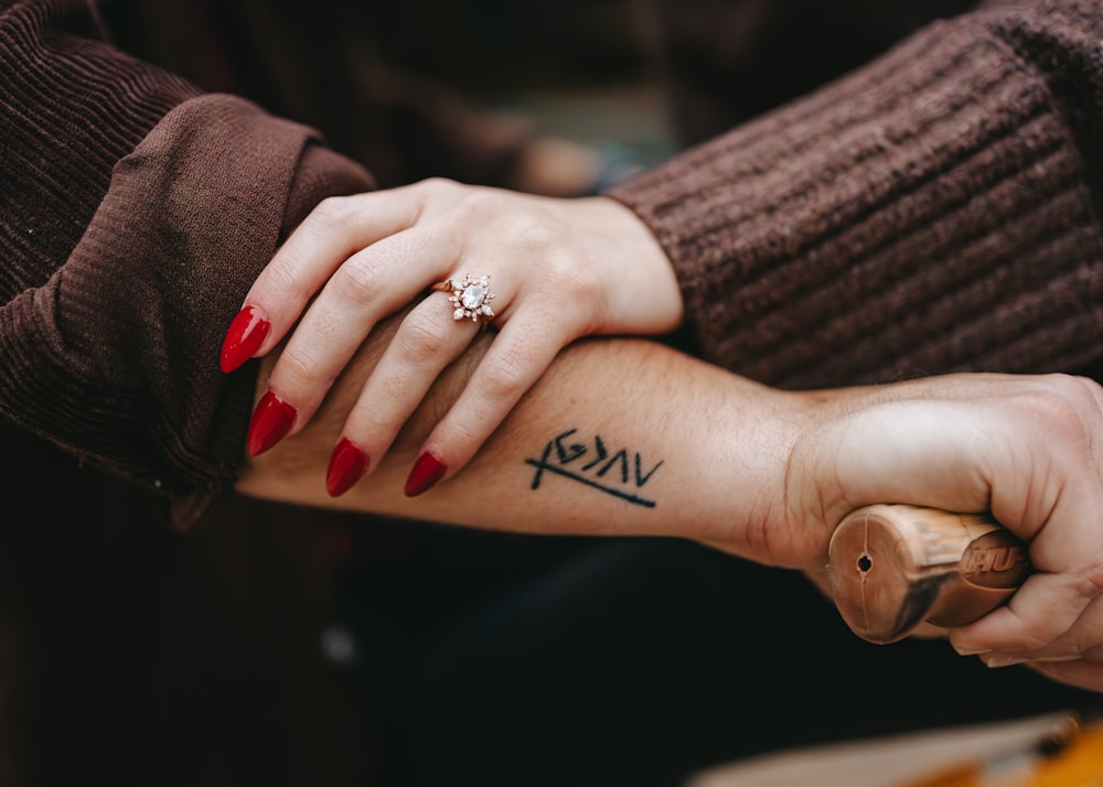 a woman with a red manicure on her arm holding the arm of a man
