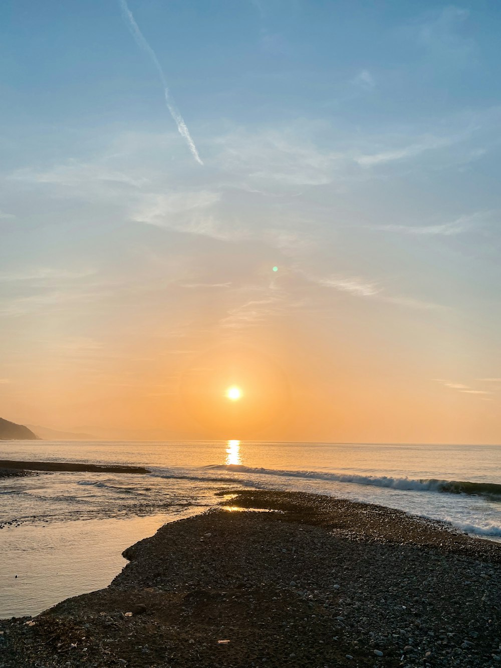 the sun is setting over the ocean on the beach