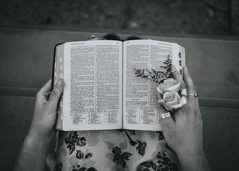 eine Person, die ein Buch mit einer Blume darauf hält