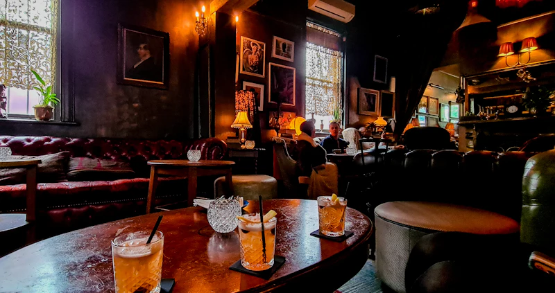 A cozy, art-deco style lounge with deep teal and cognac accents, featuring a group enjoying cigars.