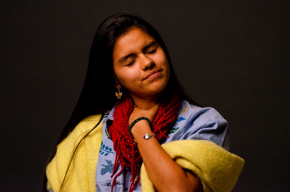 a woman wearing a yellow scarf and a red scarf around her neck